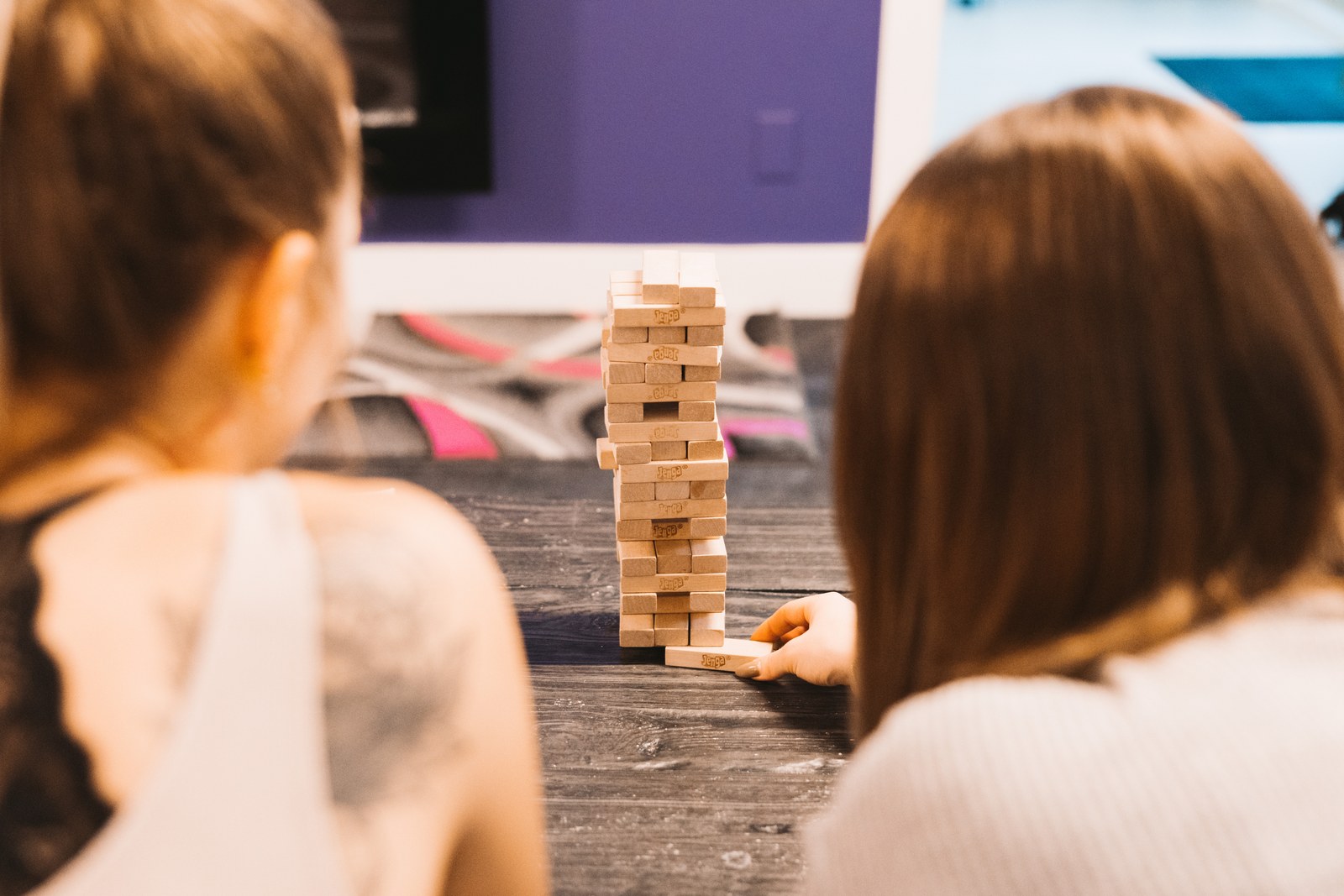 Two guests play a wooden block stacking game at a table