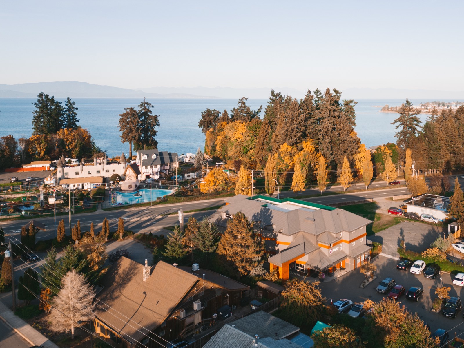 An aerial view of Coast Parksville Hotel, autumn trees and the ocean beyond the road