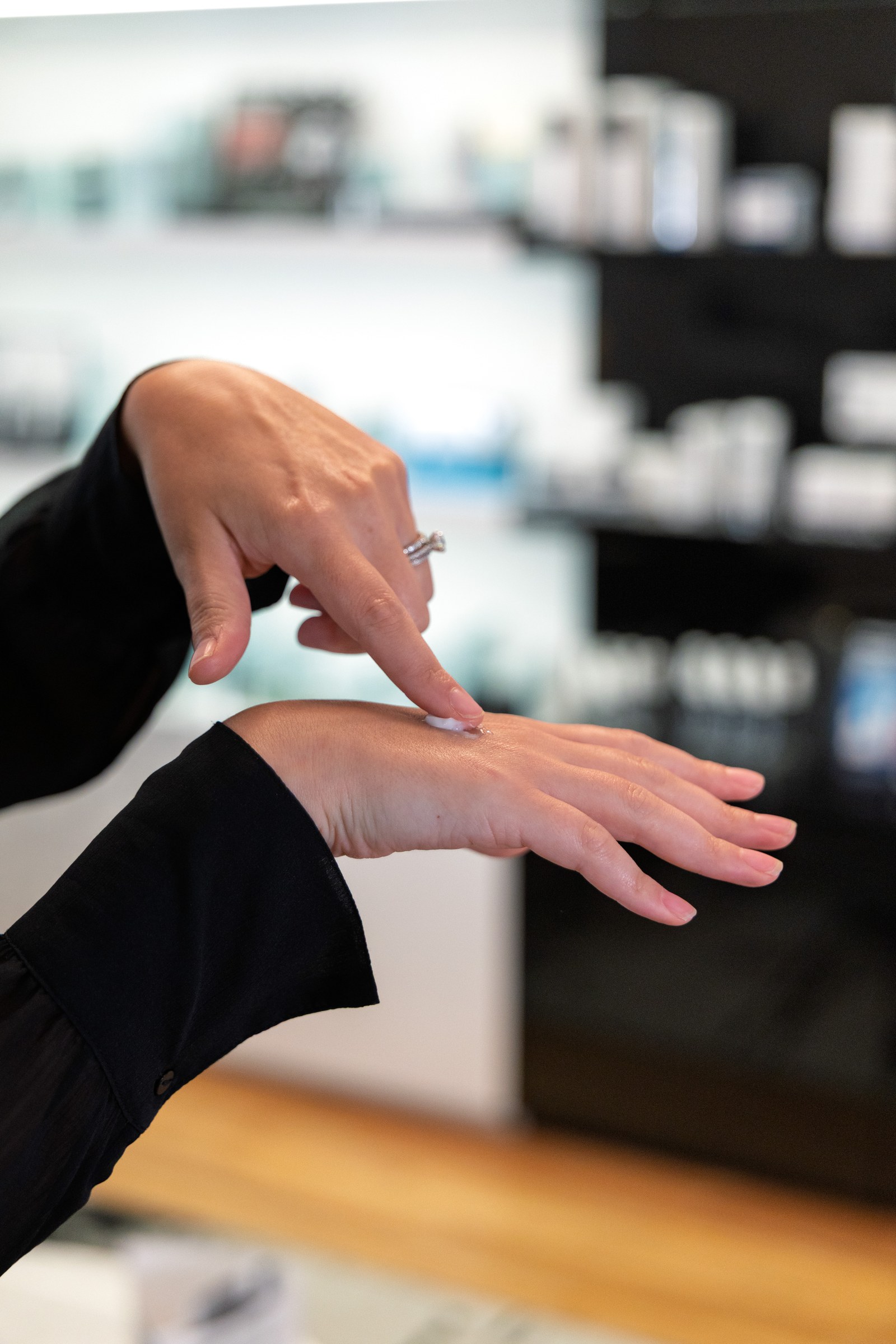 Close view of a finger applying skincare cream to the back of a hand