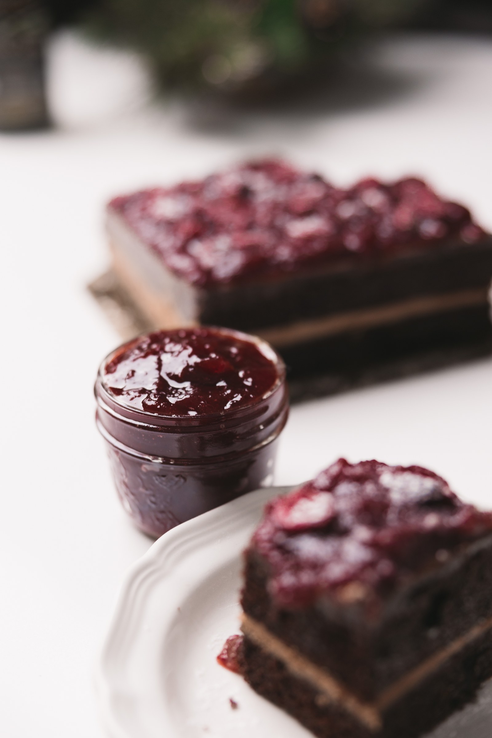 Small glass jar of cranberry sauce beside a plated layered dessert