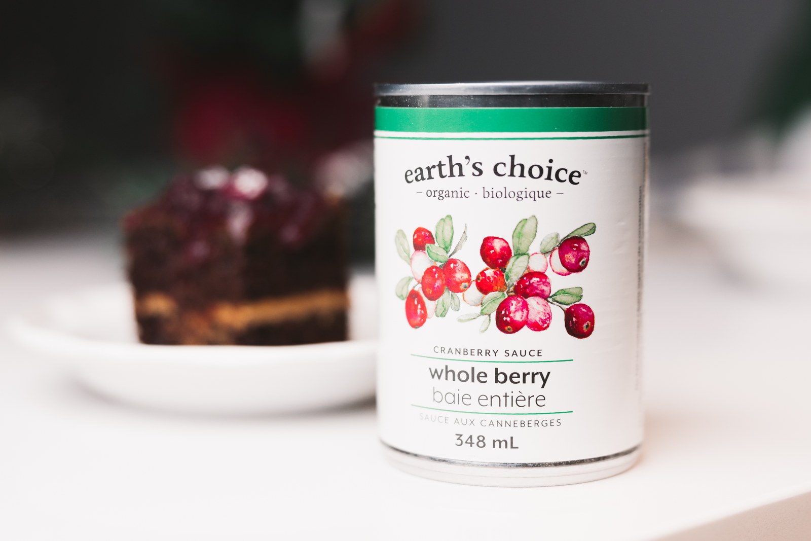 Earth’s Choice cranberry sauce can with a slice of cranberry-topped cake behind it
