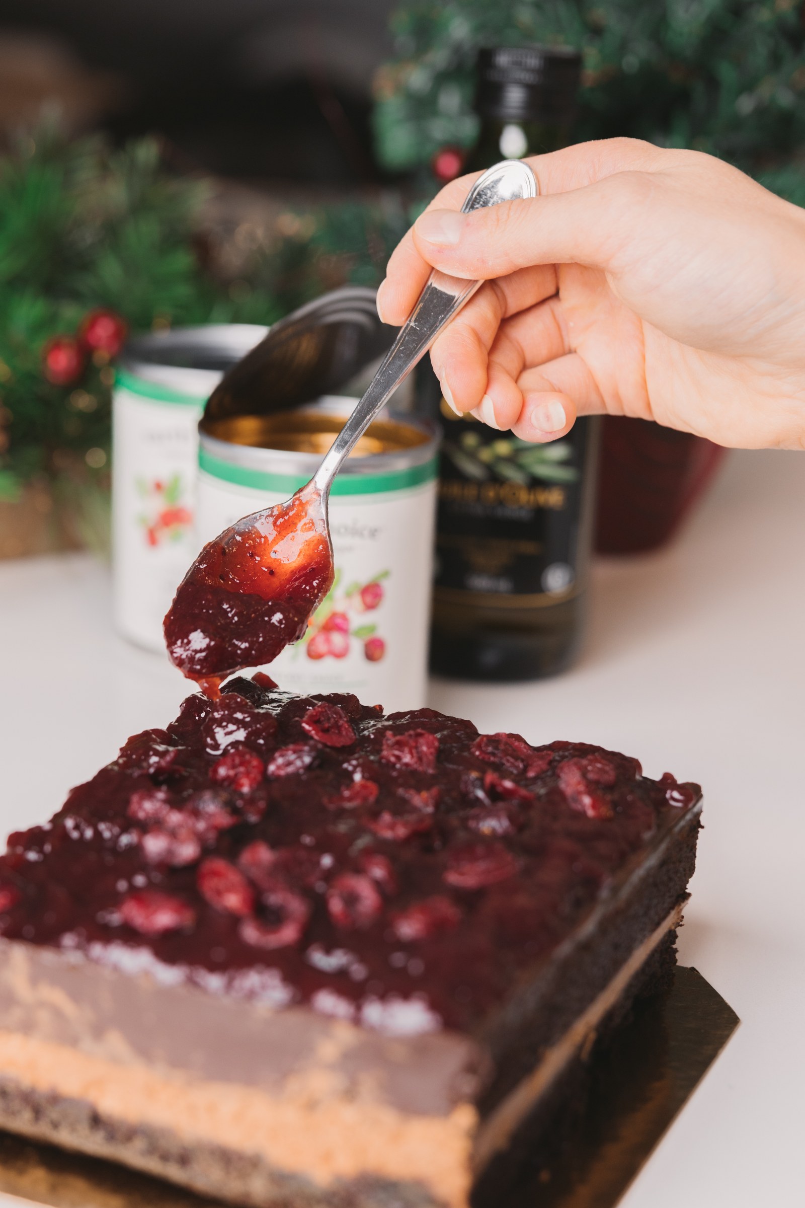 Hand adding cranberry topping to a layered dessert with Earth’s Choice products behind it