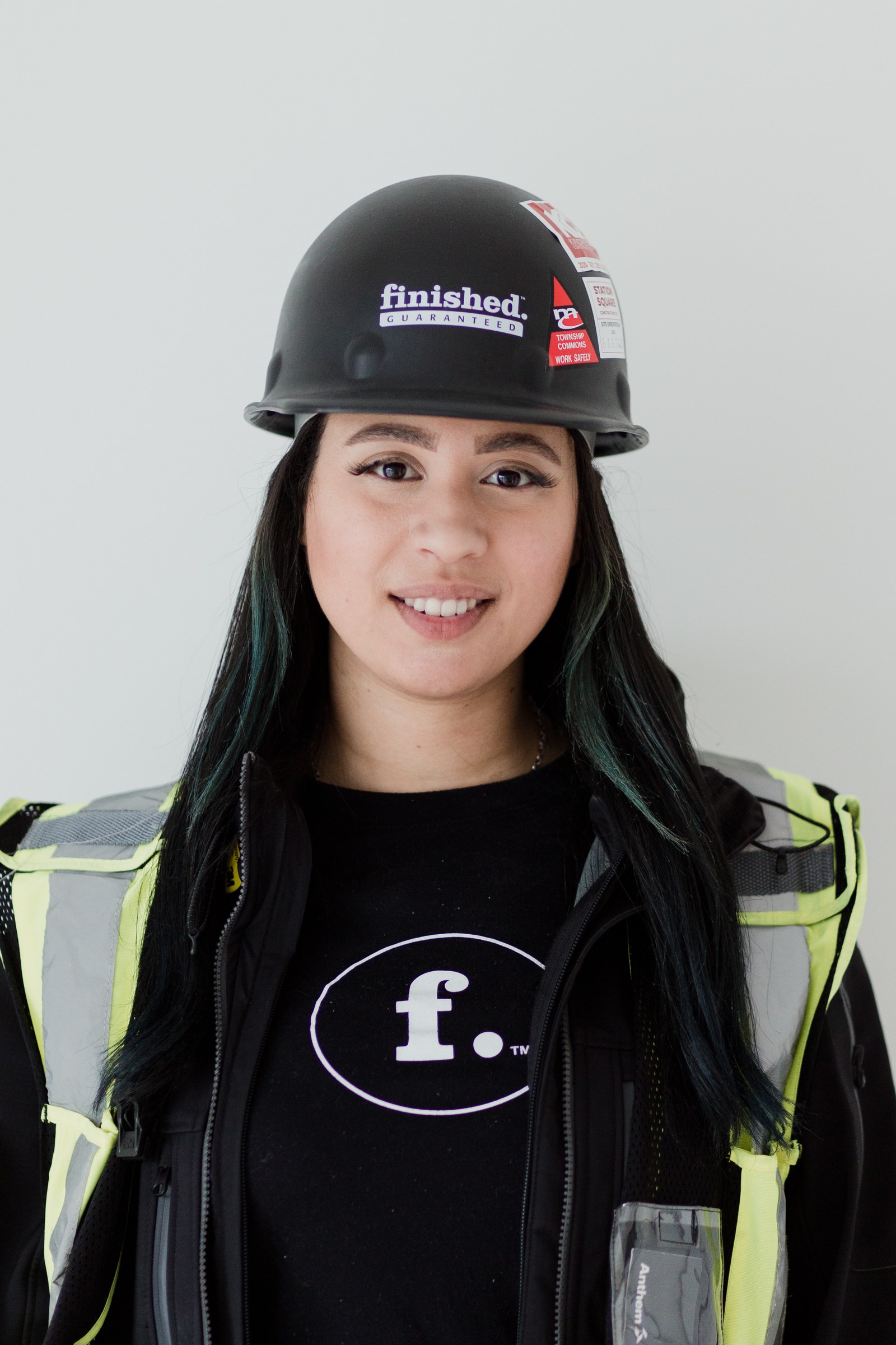 Portrait of a construction team member wearing a black hard hat and a high-visibility vest