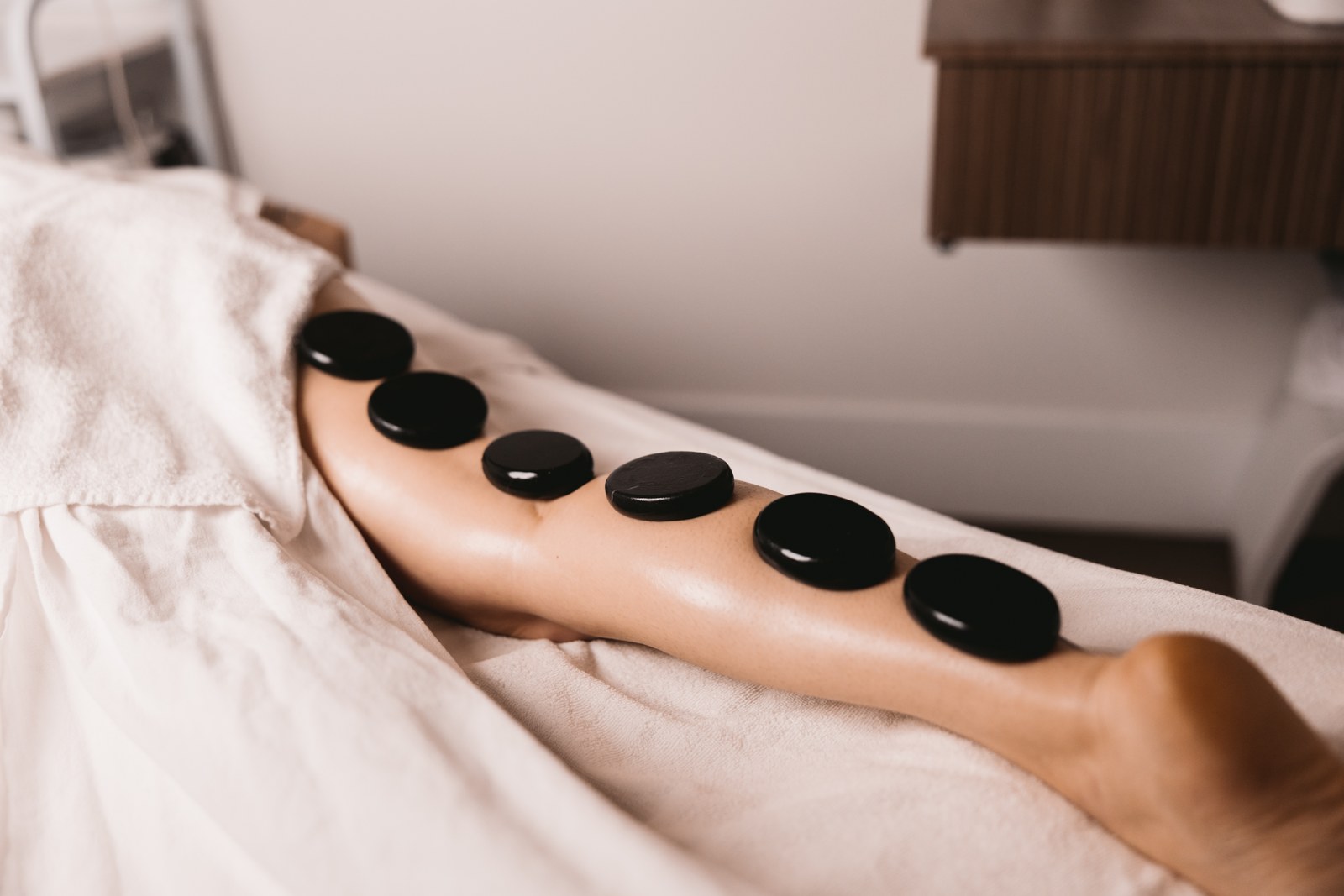 Smooth black treatment stones rest in a line on a guest’s lower leg