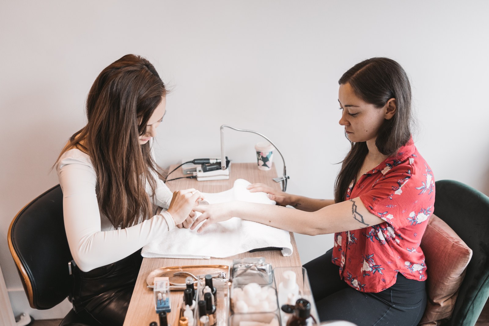 A nail technician gives a seated guest a manicure at a treatment table