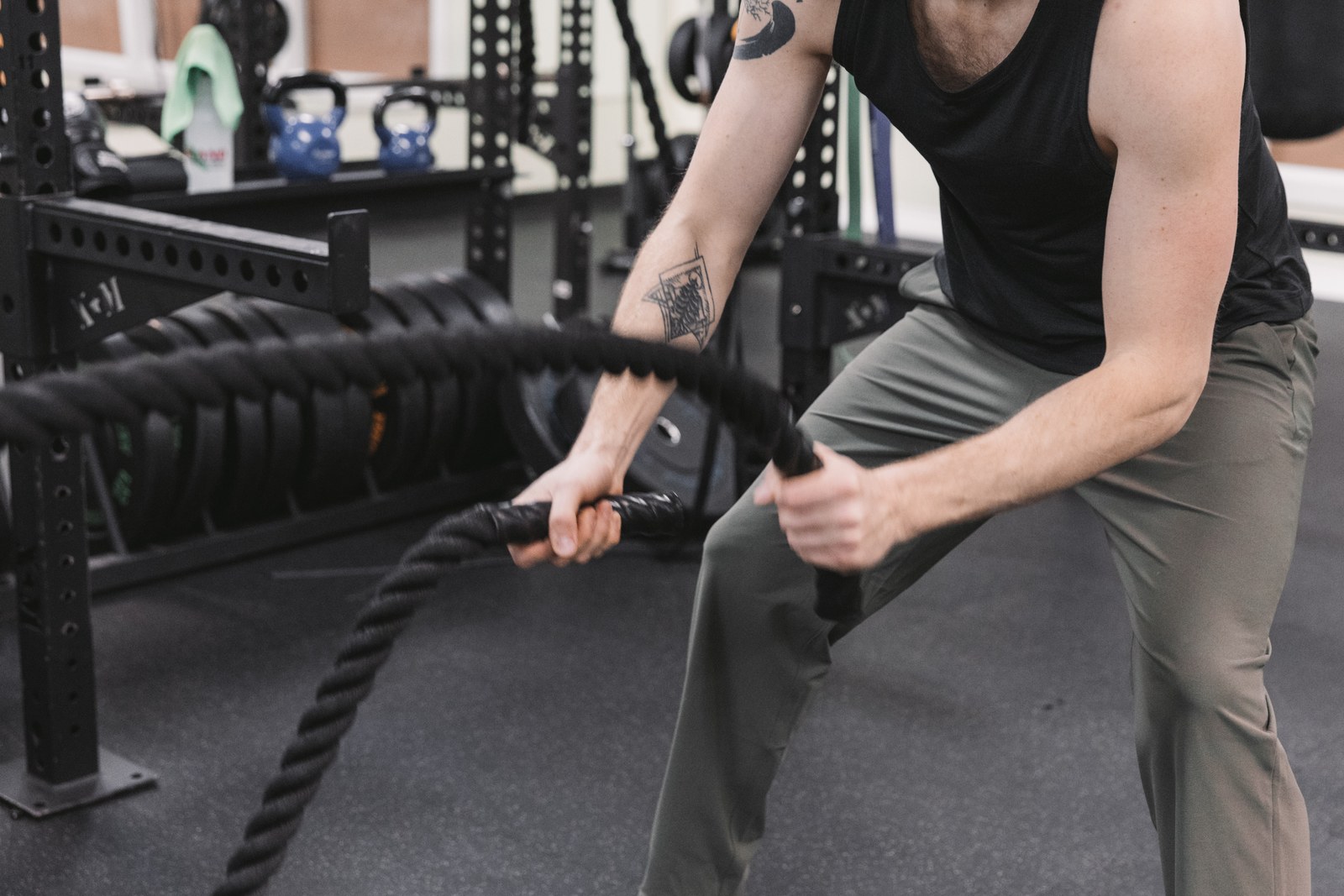 Close view of a man moving black battle ropes in a gym