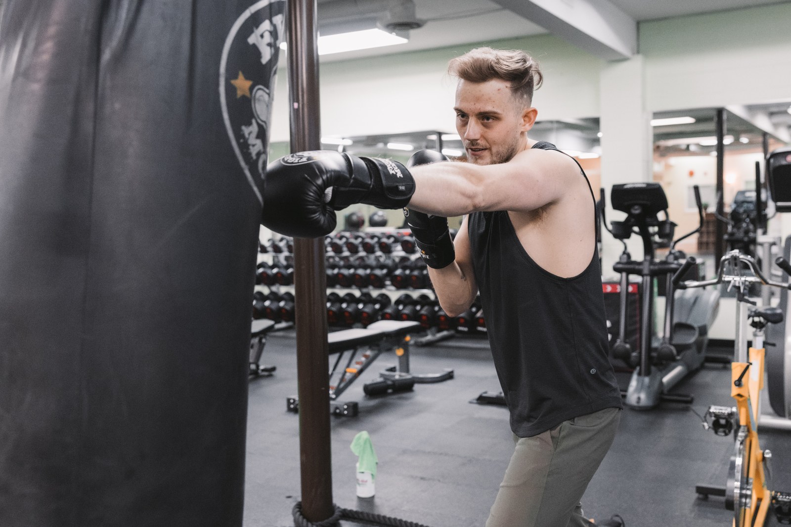 Man wearing boxing gloves punching a heavy bag in a gym