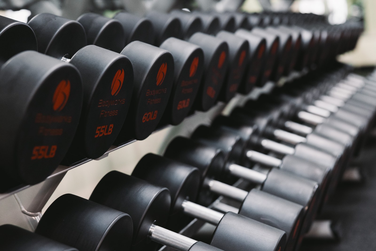 Rows of black dumbbells arranged on a gym rack