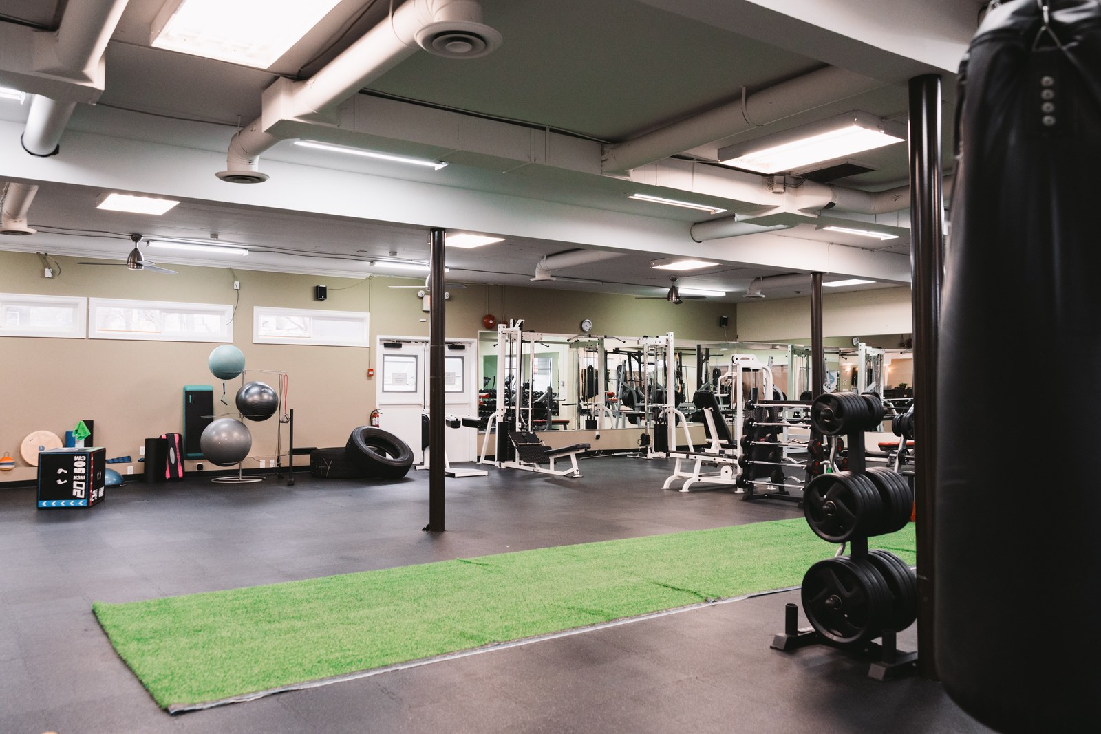 Open gym floor with a green training strip, exercise machines and free weights