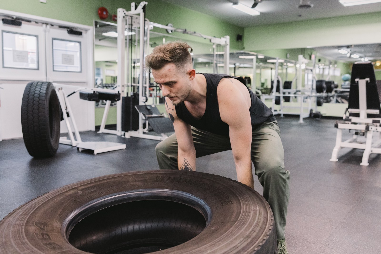 Man lifting a large training tire in a gym