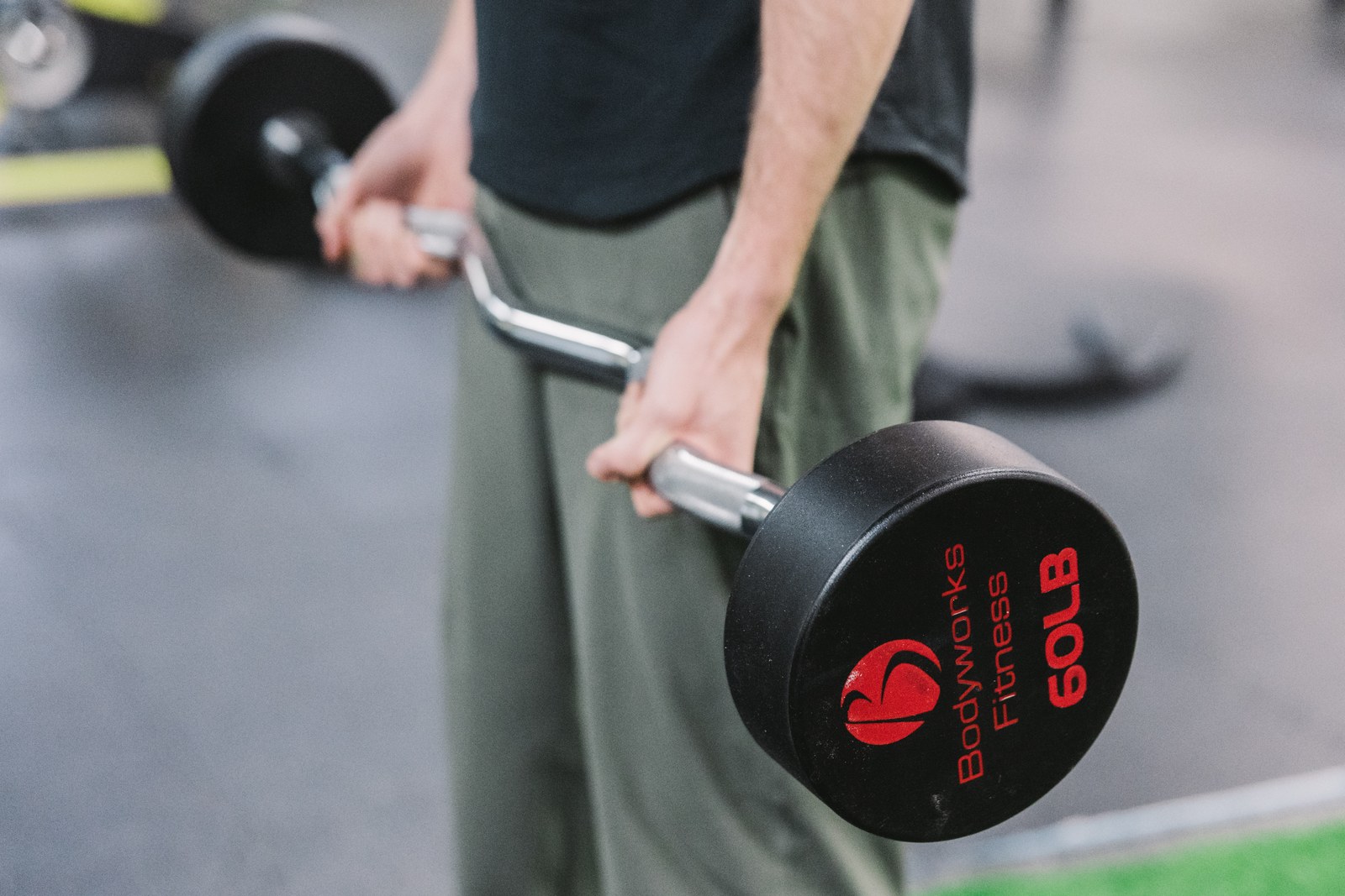 Close view of a man holding a Bodyworks Fitness weighted curl bar