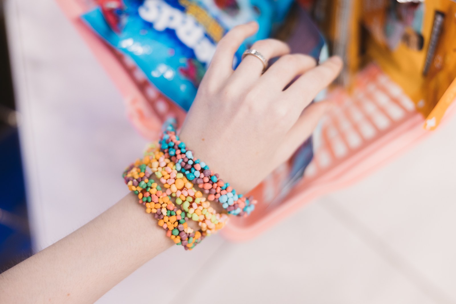 Close view of a hand wearing colourful candy bracelets inside a sweet shop