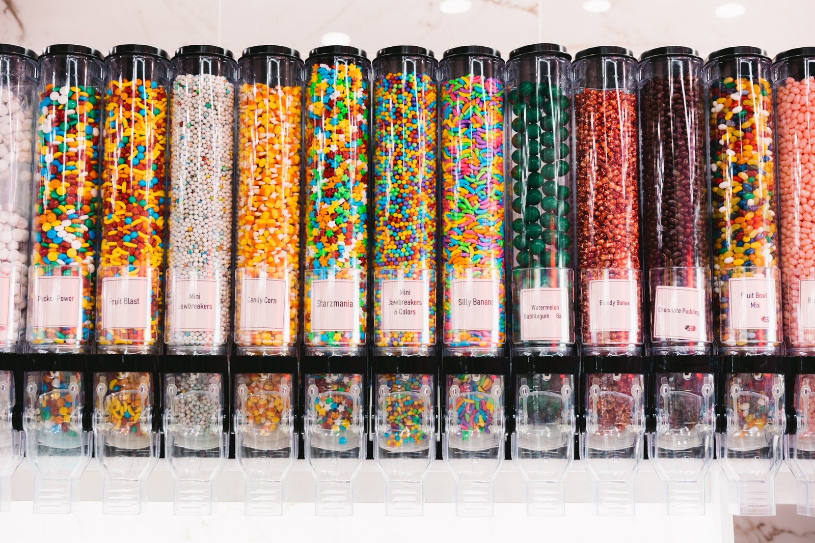 Row of clear dispensers filled with colourful sweets inside a candy shop