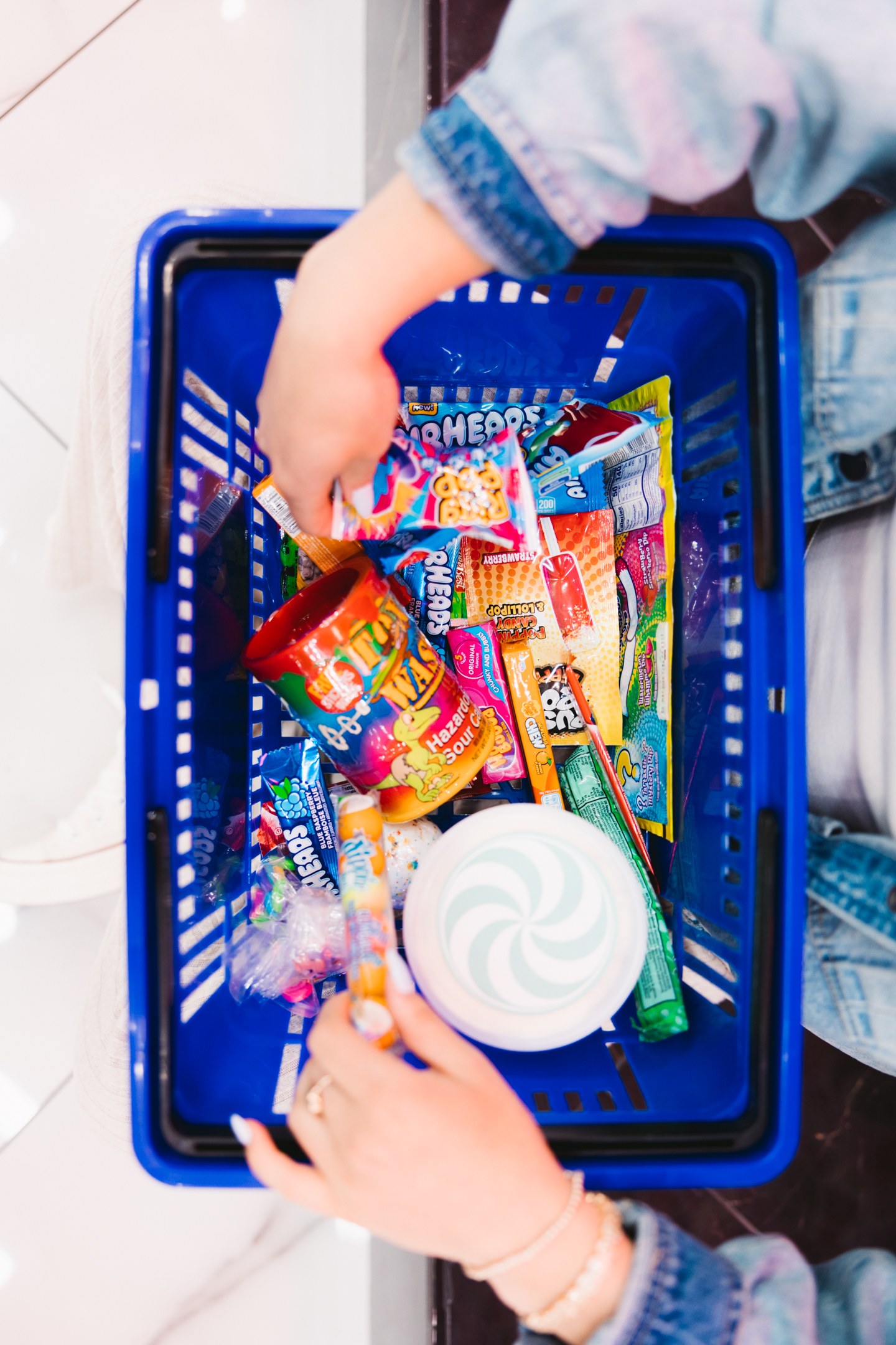 Overhead view of hands placing sweets in a blue shopping basket