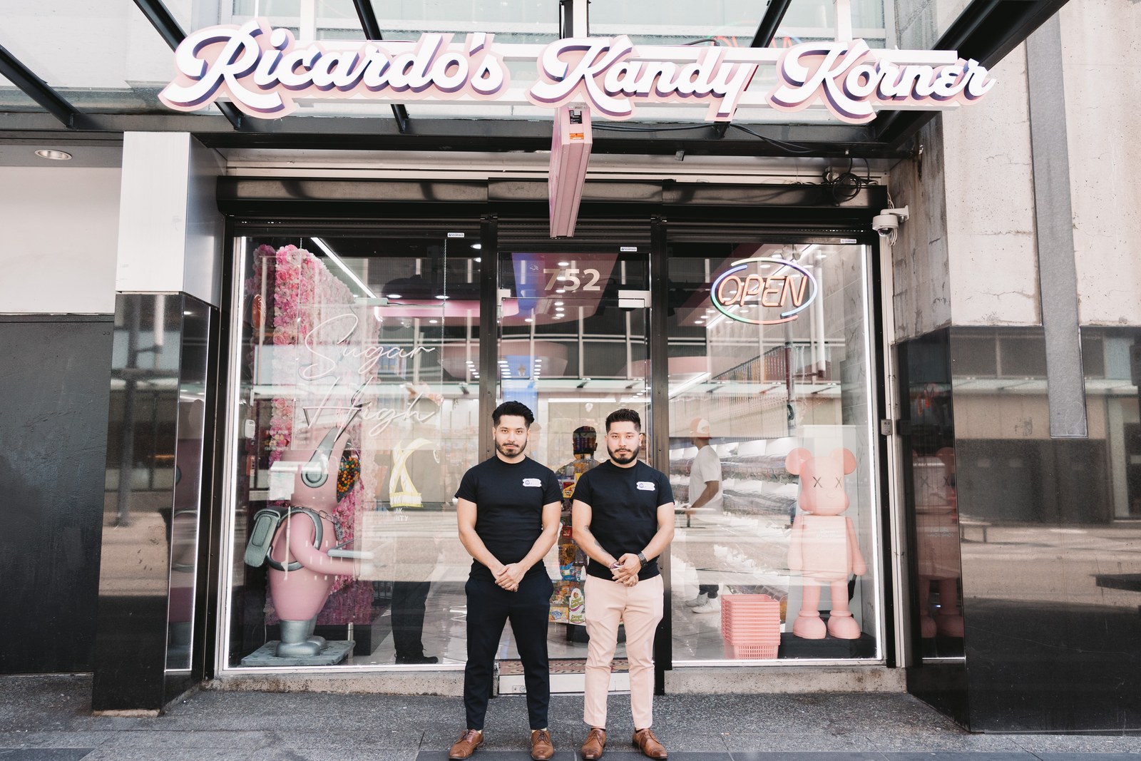 Two men standing beneath the Ricardo’s Kandy Korner storefront sign