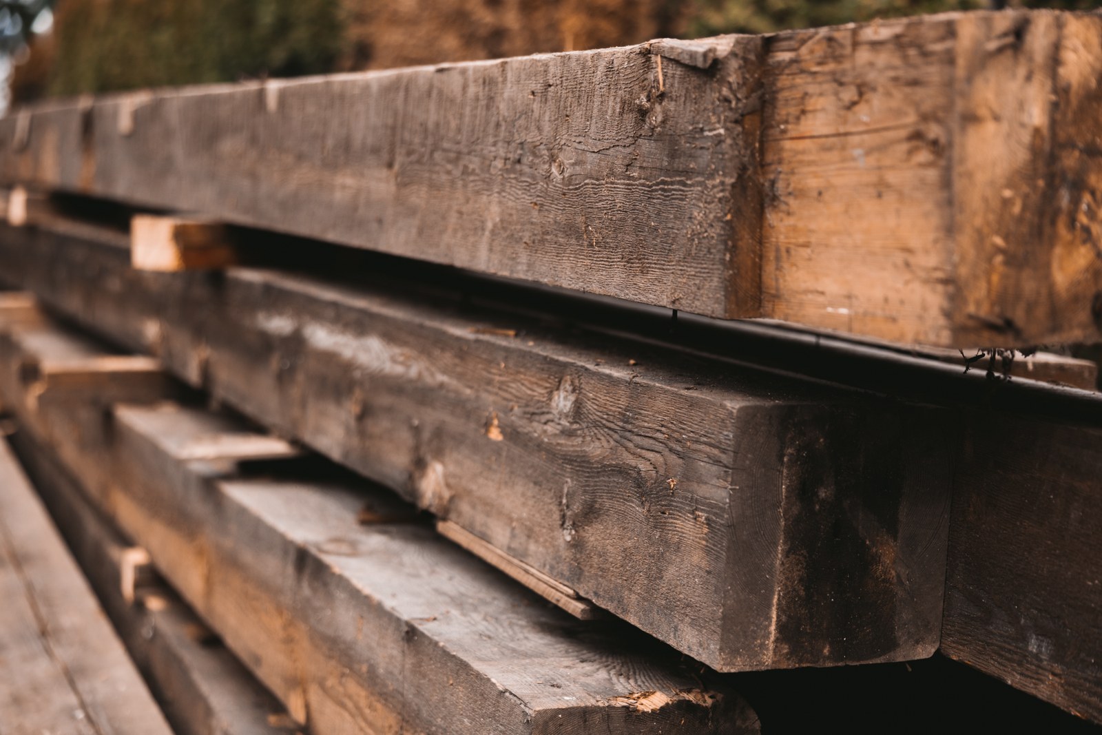 A close view of large weathered wooden beams stacked at a work site