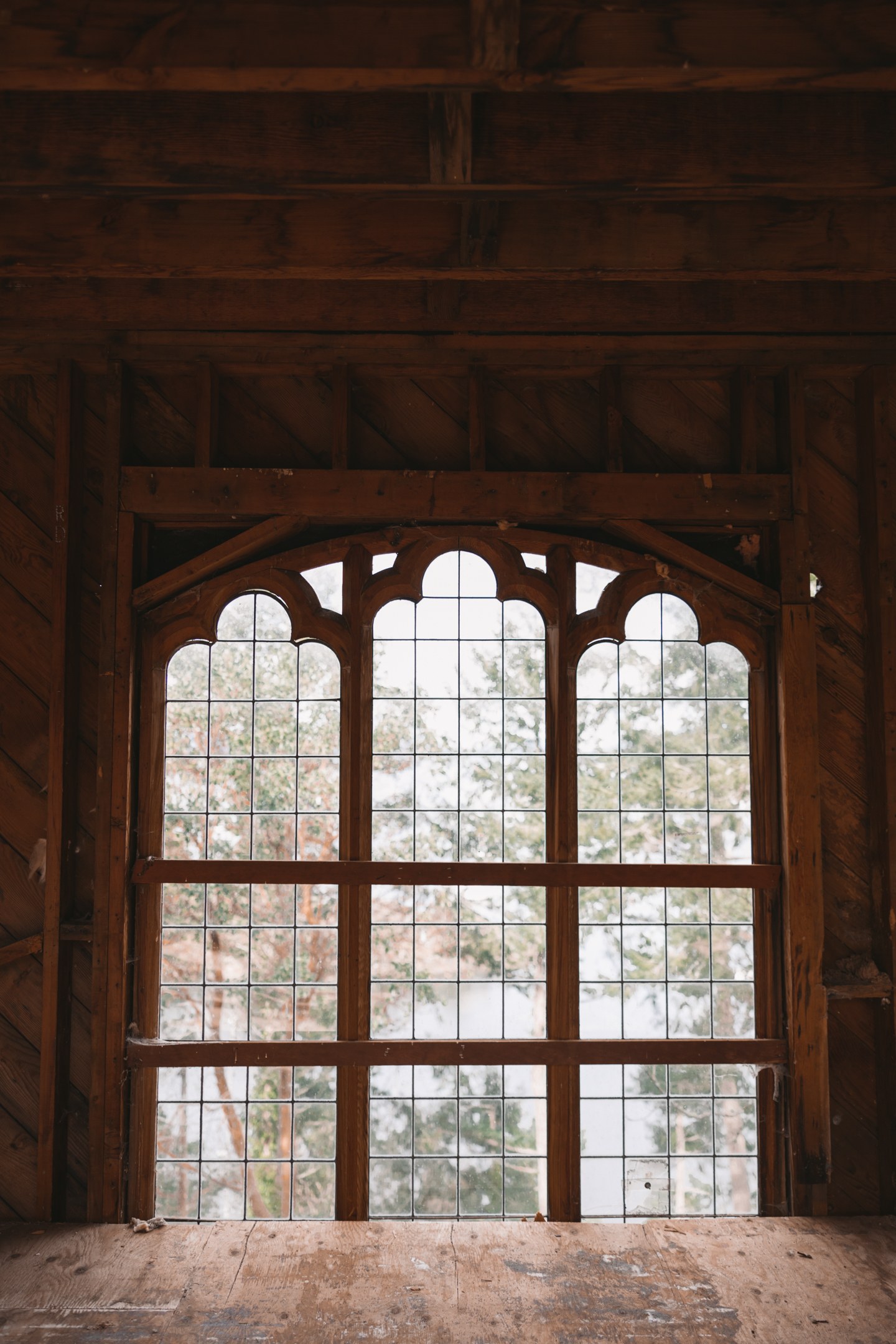 Daylight shines through an ornate leaded window surrounded by exposed wooden framing